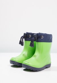 Bottes en caoutchouc vertes avec un revers en tissu bleu marine, dotées d'un cordon de serrage en haut et de semelles texturées pour une meilleure adhérence et stabilité.