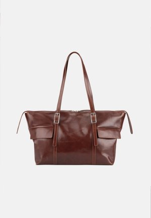 Grand sac cabas en cuir marron avec deux longues bretelles, détails de boucles à l'avant et poches latérales avec rabats sur un fond uni.