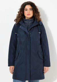 Giacca impermeabile blu navy con cappuccio, chiusura a zip, vita elastica e due tasche laterali. Tessuto liscio e materiale in nylon.