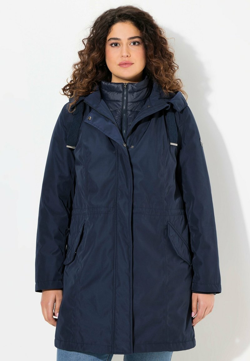 Giacca impermeabile blu navy con cappuccio, chiusura a zip, vita elastica e due tasche laterali. Tessuto liscio e materiale in nylon.