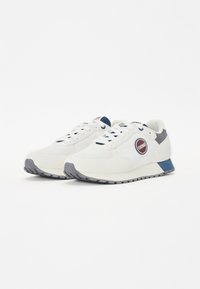 Scarpe da corsa bianche con accenti grigi e blu, dotate di una tomaia testurizzata, chiusura con lacci e un dettaglio del logo sul lato. Suola in gomma.