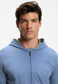 Light blue zip-up hoodie with a gray inner lining, featuring a fitted design, tonal stitching, and a small "BOSS" logo on the chest.