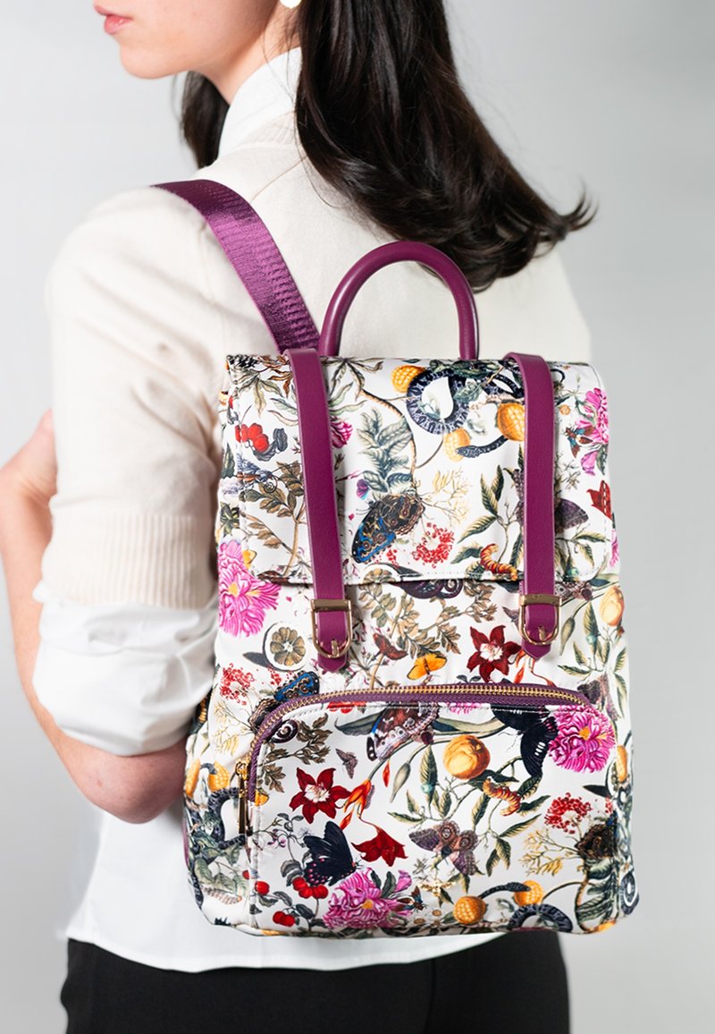 Zaino con motivo floreale, dotato di manici superiori, spallacci viola, realizzato in tessuto, e una tasca frontale con zip, che mostra fiori colorati e insetti.