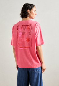 Rosa bomull t-skjorte med en avslappet passform, med et grafisk trykk i livlige farger på baksiden, og korte ermer.