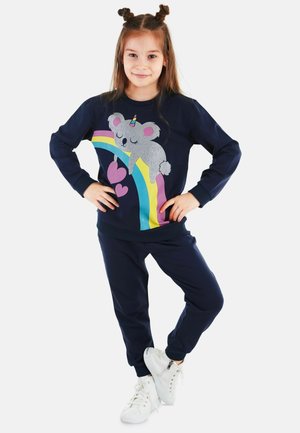 Marineblauer, langärmeliger Pullover mit einem Koala- und Regenbogen-Motiv; kombiniert mit passenden Hosen und weißen Sneakers. Weiches Material, lässige Passform.