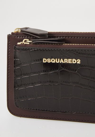 Black crocodile-embossed leather wallet features a gold "DSQUARED2" logo, double zip compartments, and brown stitching accents.