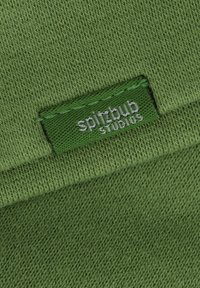 Grüner Stoff mit einer gestrickten Textur, der ein Etikett enthält, auf dem "spitzbub studios" in Weiß auf einem passenden grünen Hintergrund steht.