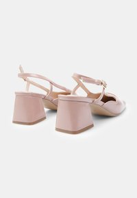 Pink patent leather block-heeled sandals with ankle strap, open toe, and crisscross back design. Flat textured sole for grip.