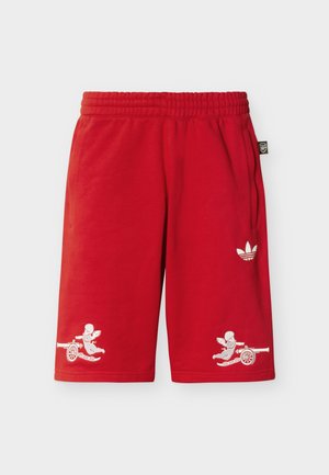 Punased lühikesed püksid kummiga vöökohal, küljetaskutega, valge Adidas logo paremal jalal ning kummagi jala ääres hemli juures delfiinikujulised kujufiguurid, kes tulistavad kahureid.