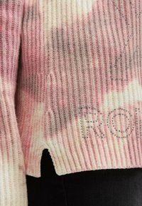 Strickpullover in Pink- und Cremetönen, mit geripptem Struktur, ausgeschnittenem Saum und verziert mit silbernen Strasssteinen, die "RON" buchstabieren.
