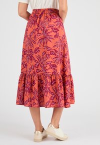 Maxi rok in koraal met een bloemenprint in bordeauxrood en wit. Heeft een gerimpelde taille en een rucheszoom, gemaakt van lichtgewicht stof.