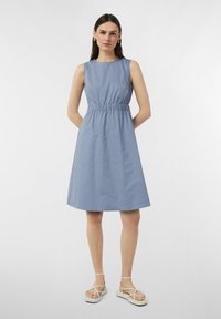 Hellblaresses ärmelloses Kleid mit gerüschter Taille, A-Linie-Form und glatter Textur. Kombiniert mit weißen Riemchensandalen.