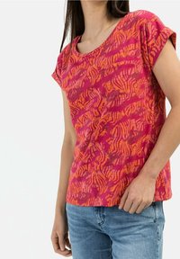Camiseta de manga corta en vibrante rosa y naranja con un patrón texturizado en forma de ola. Material de algodón, corte relajado, escote redondo.