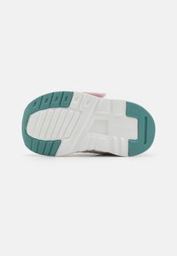 Shoe outsole features a textured white base with teal accents and grooves for grip. Material appears rubbery with a modern design.