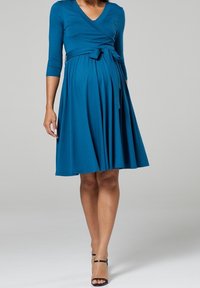 Tyrkysové šaty s překřížením a třičtvrtinovými rukávy, šňůrkou v pase a rozšířenou sukní. Hladká textura a výstřih do V.