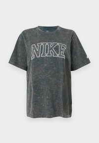 Tmavo šedé bavlnené tričko s veľkým bielym grafickým nápisom "NIKE" na prednej strane. Uvoľnený strih s krátkymi rukávmi a okrúhlym výstrihom.