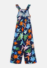 Bloemen jumpsuit van marineblauwe stof met een smock-buste, rufflespannelen en levendige tropische bloemenpatronen in meerdere kleuren.