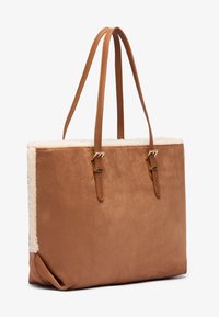 Sac fourre-tout en faux daim marron avec doublure en fourrure crémeuse, deux poignées plates et accents en métal. Le design est rectangulaire avec une texture douce.
