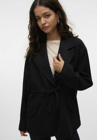 Must mustriba pehmeast kangast, vööga talje, laiade sügavate krae ja küljetaskutega. Sile tekstuur, lõdvestunud istuvus.