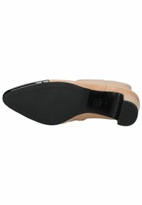 Zapato de charol nude con punta afilada y suela de goma negra. Presenta una puntera brillante y un tacón bajo, diseñado para comodidad y estabilidad.