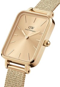 Montre rectangulaire dorée avec un bracelet en maille texturée, présentant un cadran en rayon de soleil et des index horaires minimalistes. Logo imprimé sur le cadran.