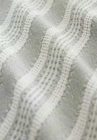 Tejido textil con rayas alternas en gris claro y blanco, con un tejido texturizado que crea un aspecto ondulado y un patrón de rejilla.