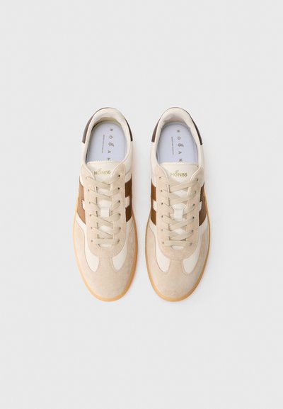 Zapatillas de ante y cuero beige con acentos marrones, suela de goma, cordones y logotipo de la marca en la lengüeta y el lado lateral.