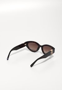 Tortoise-shell sunglasses with brown lenses, cat-eye shape, gold accent on temple, smooth texture, and contrasting colored tips.