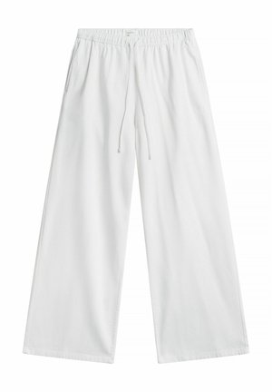 Valkoiset leveälahkeiset housut, joissa on joustava vyötärönauha ja kiristysnauha, sivutaskut, aseteltuna tasaiselle valkoiselle taustalle.