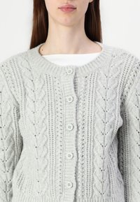 Light gray knitted cardigan featuring a textured cable pattern, five button closure, and ribbed collar and cuffs.