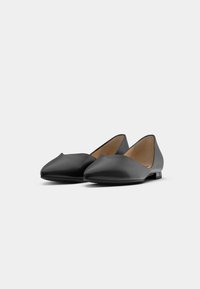 Black flat shoes made of smooth leather, featuring a pointed toe, low heel, and triangular cutouts on the sides for a sleek design.