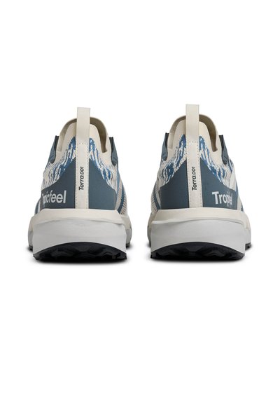 Paire de chaussures de sport bleu et blanc avec tissu à motifs, languettes marquées « Terra.001 » et semelles blanches épaisses vues de dos.