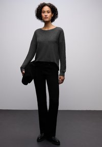 Harmaa pitkähihaisen paita rento istuvuus, yhdistetty suoralahkeisiin mustiin housuihin. Sileä kangas, yksinkertainen muotoilu, ei näkyviä kuvioita tai koristeita.