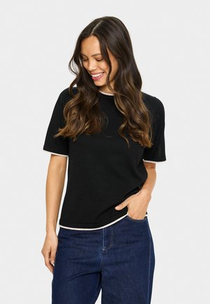 T-shirt noir avec un col rond, des manches courtes et un ourlet contrastant de couleur claire. Le tissu semble doux avec une coupe décontractée. Associé à un jean bleu.