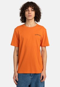 Camiseta de algodón naranja de manga corta, con un pequeño logo negro de "ELEMENT" en el pecho. La tela tiene una textura suave.