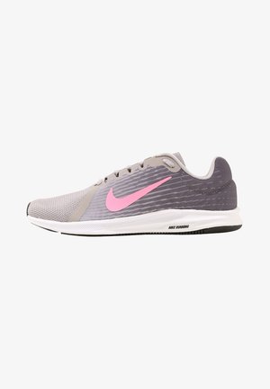 Šedá běžecká bota s texturovaným síťovaným svrškem a růžovým logem Nike. Obsahuje bílou mezipodešev a černou gumovou podešev. Nízký profil.