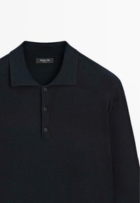 Mørkeblå langærmet polo shirt med flad krave, fire-knap lukning og blød, struktureret stof. Mærkeetiket synlig ved halsen.