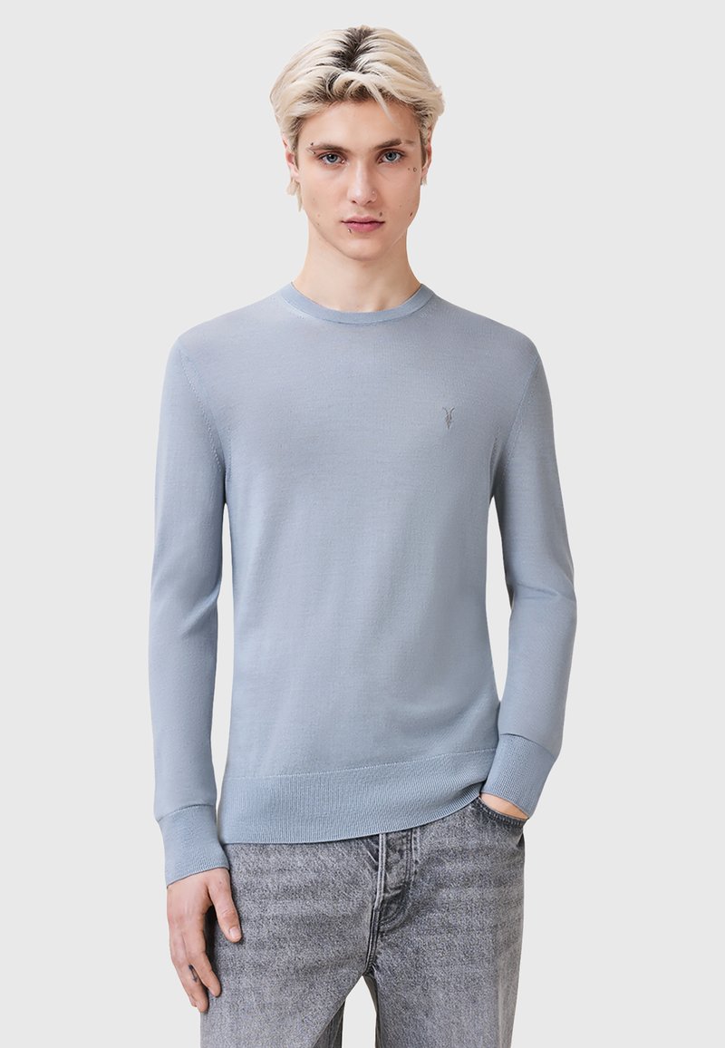 Maglione lavorato a maglia blu chiaro con scollatura rotonda, maniche lunghe e polsini a costine. Presenta un logo discreto sul petto e una texture liscia.