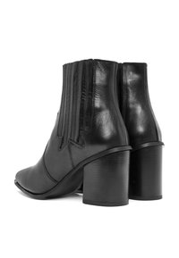 Botas de tobillo de cuero negro con puntera afilada, tacón de bloque sólido y paneles laterales elásticos con detalles de costura. Textura suave.