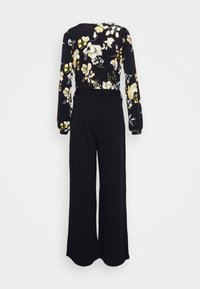 Macacão preto com mangas longas, padrão floral em amarelo e branco, parte superior ajustada, pernas largas e largas, tecido suave, vista traseira.