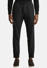 Pantaloni sport de culoare neagră, cu un brâu elastic și detalii cu șnur. Au picioare conice cu mansete elastice și două buzunare frontale.