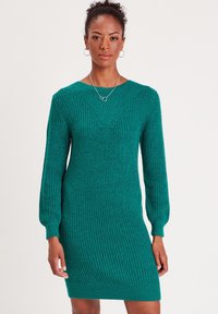 Vestido de punto en color teal con diseño en forma de V, mangas largas y dobladillo acanalado. La textura de la tela es prominente, proporcionando un aspecto casual pero estructurado.