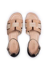 Beige lederen sandalen met een vierkante neus, voorzien van gevlochten banden en een zwarte hielaccent. Inclusief een verstelbare enkelriem voor sluiting.