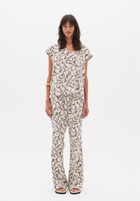 Completo a due pezzi composto da un top a maniche corte e pantaloni larghi, realizzato in tessuto leggero con un motivo floreale in toni di nero e beige.