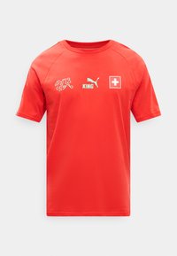 Κόκκινο αθλητικό T-shirt με κοντά μανίκια, λευκό λογότυπο Puma, κείμενο «KING», έμβλημα της Ελβετικής Ομοσπονδίας Ποδοσφαίρου και τη σημαία της Ελβετίας στο στήθος.