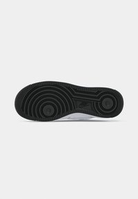 Nike sneakersåle har en teksturert svart gummi med sirkulære mønstre og riller, som gir godtgrep og holdbarhet.