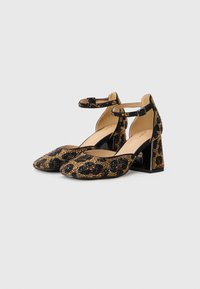 Leopard print high heels with a textured surface, ankle strap, and chunky square heel. Colors include black, brown, and gold accents.