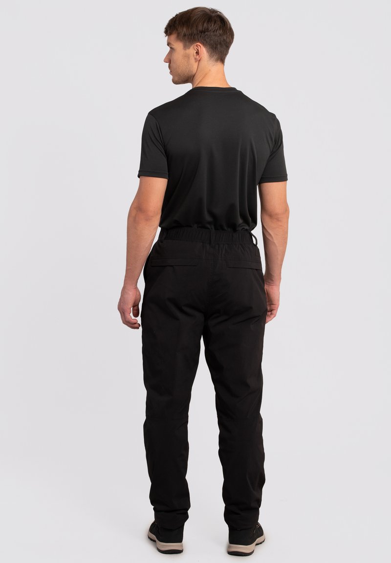 Czarne spodnie sportowe z elastycznym pasem, dwoma bocznymi kieszeniami i zwężającym się krojem, zestawione z dopasowaną czarną koszulką z krótkim rękawem.