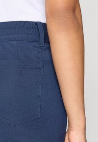 Τα αθλητικά παντελόνια σε ναυτικό μπλε χρώμα διαθέτουν ελαστική μέση και  πίσω τσέπη με μικρό λογότυπο. Το ύφασμα έχει λεία υφή και καθημερινό σχεδιασμό.