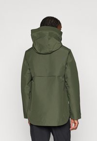 Casaco verde impermeável com capuz, apresentando um fecho de zipper e dois bolsos laterais. Textura suave e uma barra ligeiramente curvada.